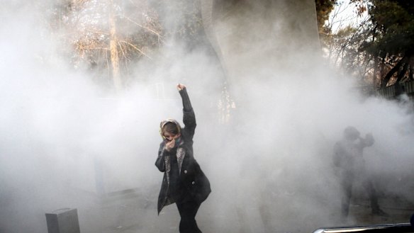 In this photo obtained but not taken by the Associated Press, a university student attends a protest last week inside Tehran University while a smoke grenade is thrown by anti-riot Iranian police.