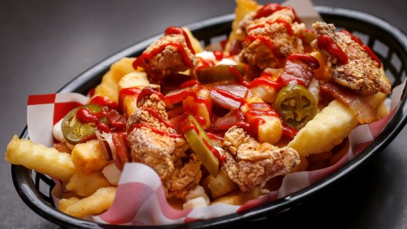Tabarnak poutine, with house-made cheese curds and gravy, jalapenos, sriracha, buttermilk fried chicken and bacon.