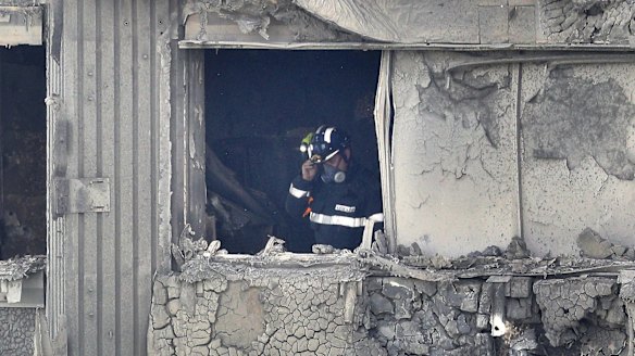 A firefighter conducts a search of a burnt-out flat in Grenfell Tower.