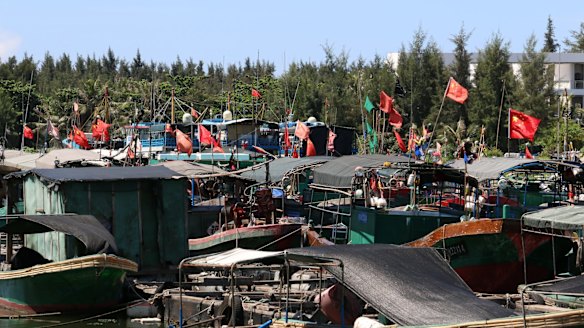 Fishing vessels moored at Tanmen wharf fly the flag of the People's Republic.