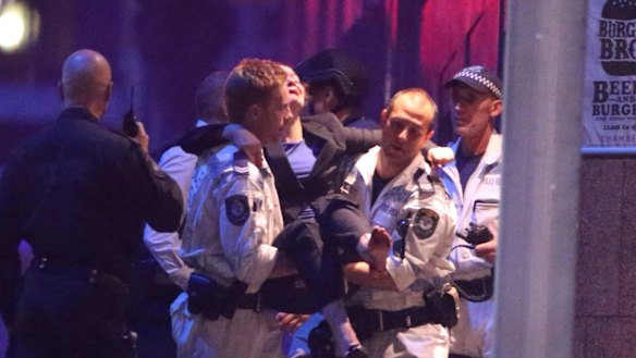 A woman is carried away from the Lindt Chocolat Cafe in Martin Place.