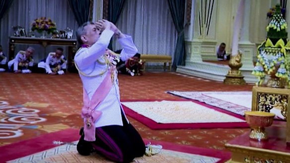 Then Crown Prince Maha Vajiralongkorn kneels under a portrait of his late father at the Grand Palace in Bangkok on December 1.