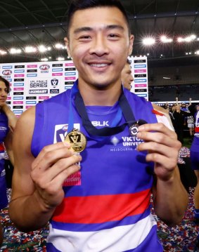 Lin Jong holds his best on ground and premiership medals after the VFL grand final.