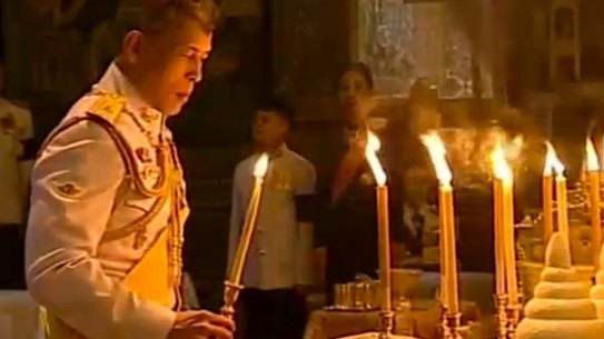 The Thai King lights candles during a religious ceremony at the Grand Palace where the remains of his father lie.