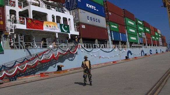 A Pakistan Navy soldier stands guard while a loaded Chinese ship prepares to depart from Gwadar port.