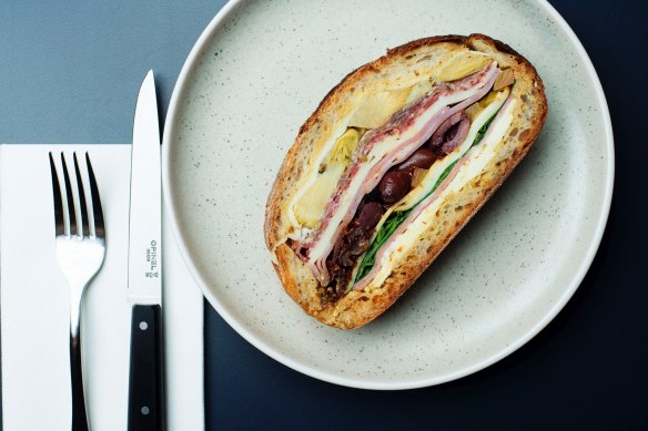 The muffuletta, a pressed baguette of olive, mortadella, salami, ham, provolone, peppers and artichokes.