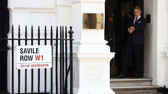 An employee at the entrance to Gieves & Hawkes, a tailoring store on London's Savile Row.