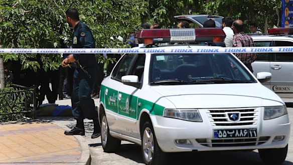 The body of a terrorist, at background left, lies on the ground while police control the scene at the shrine of late Iranian revolutionary founder Ayatollah Khomeini, just outside Tehran on Wednesday.