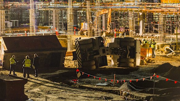 Police, ambulance, and worksafe on the UC Hospital Building site where a crane is lying on its side.