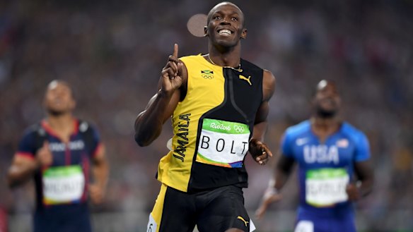 Three-time champion: Usain Bolt celebrates winning the 100m final, with Justin Gatlin, right, finishing second.