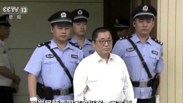 Zhai Yanmin is escorted by policemen as he arrives at the Tianjin court.