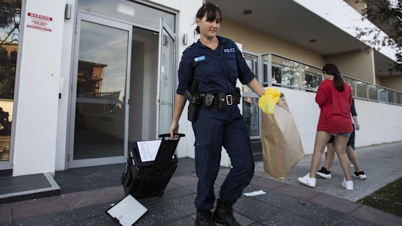 A police officer removes evidence from Michelle Leng's Campsie home.