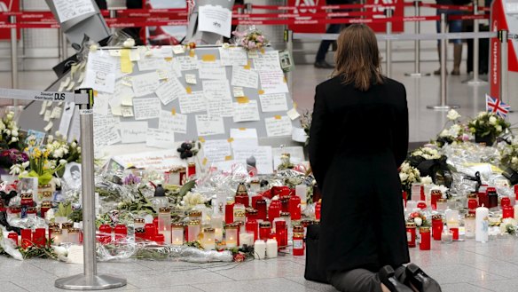 A woman kneels in front of candles and flowers as she prays for the victims of Germanwings Flight 4U9525 at Dusseldorf airport on April 1.