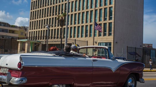 Tourists ride a classic convertible car on the Malecon beside the United States Embassy in Havana, Cuba.