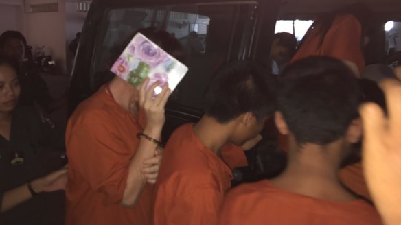 Tammy Davis-Charles hides her face as she is led back to her jail cell from Phnom Penh court on Thursday.