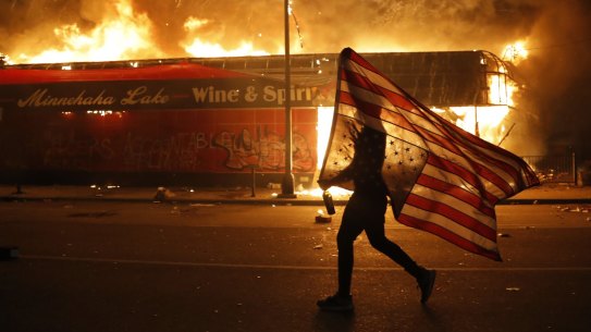 A protester carries a U.S. flag upside down.