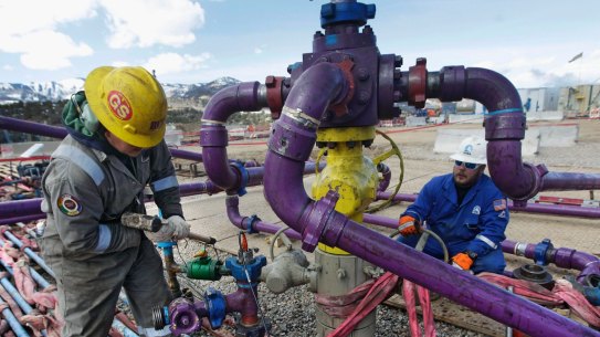 Workers tend to a well head during a hydraulic fracturing operation outside Rifle, Colorado. 