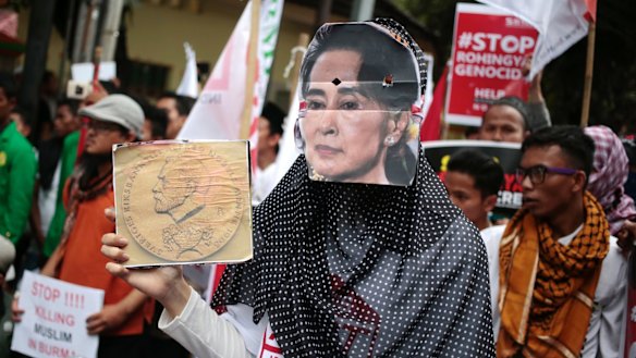 A Muslim woman wears a mask of Myanmar's Foreign Minister Aung San Suu Kyi during a rally against the persecution of Rohingya Muslims last month.