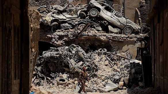 An Iraqi Special Forces soldier walks in front of a wall of debris on a road in West Mosul, Iraq.
