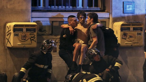 French fire brigade members aid an injured individual near the Bataclan following fatal shootings in Paris.