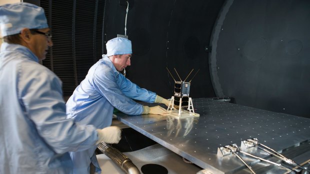 Mike Petrovic (left) and Bart Fordham from ANU load a CubeSat into the space simulator at the ANU Advanced Instrumentation and Technology Centre.