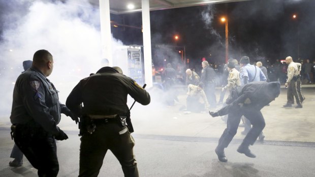 Police try to control an angry crowd at the gas station where the shooting took place.