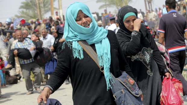 Displaced Sunni women fleeing the violence in Ramadi, carry bags as they walk on the outskirts of Baghdad. 
