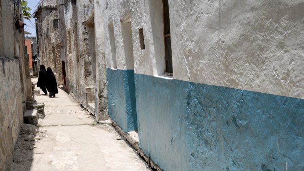 Women walk down a narrow alley of the Old Town on Lamu Island, a UNESCO World Heritage Site.