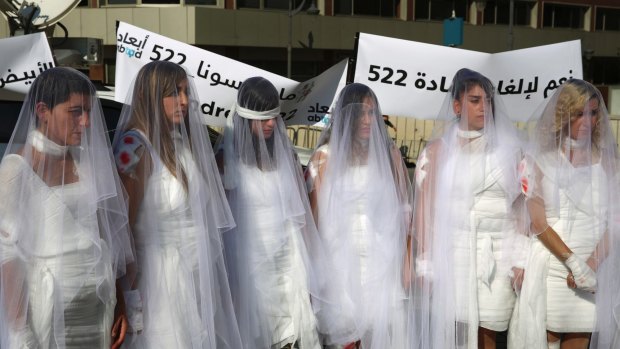 In this December 6, 2016 file photo, Lebanese women, dressed as brides in white wedding dresses stained with fake blood, protest against article 522 in the Lebanese penal code that stipulates that a rapist is absolved of his crime if he marries his victim, in front of the government building in downtown Beirut, Lebanon.