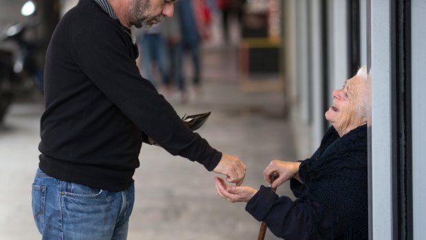 An elderly lady begs for money on the streets of Athens.