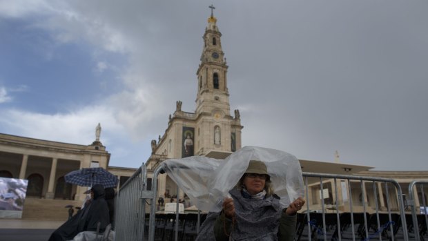 FATIMA, PORTUGAL - MAY 11: A worshipper takes cover from the rain as she waits for the Pope Francis visits at the Sanctuary of Fatima on May 11, 2017 in Fatima, Portugal. Pope Francis will be attending the Sanctuary of Fatima, in Portugal, on May 12 and 13 to canonize two Portuguese shepherds, Jacinta and Francisco Marto, who are said to have witnessed the apparition of what they believed was the Virgin Mary, together with their aunt Lucia Santos, during the 100 anniversary. Thousands of pilgrims are expected to gather to the centenary celebration. (Photo by Pablo Blazquez Dominguez/Getty Images)