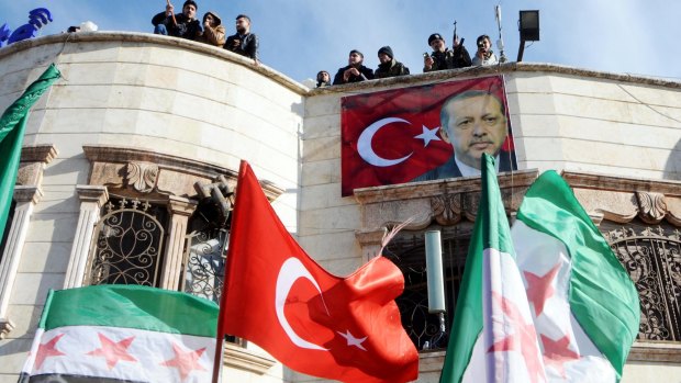 Turkey-backed Free Syrian Army fighters stand on the roof of a building with a poster of Turkey's President Recep Tayyip Erdogan.