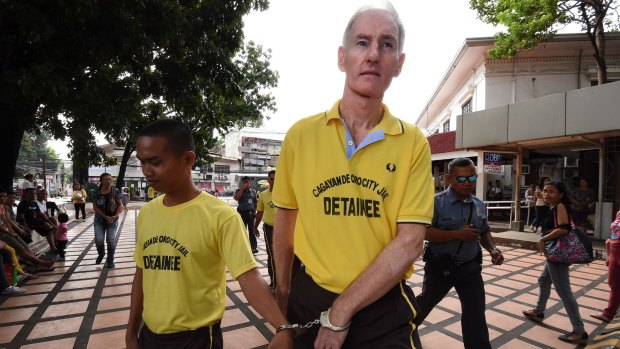 Peter Scully (right) arrives at the Cagayan De Oro court handcuffed to another inmate on the first day of his trial. 