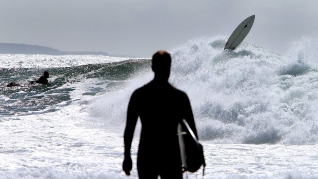 A surfer comes unstuck  in the surf off Sandon Point at Bulli as the east coast of New South Wales is battered with high winds and a predicted four-metre swell.