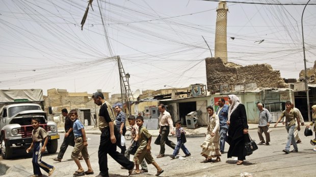 Residents walk past the tilted minaret of al-Nuri mosque in busy market area in Mosul, Iraq in 2009.