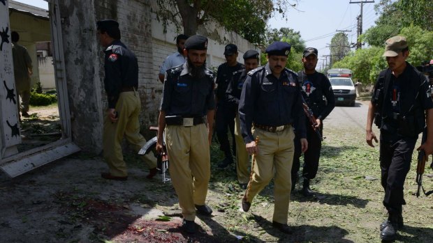 Pakistani police officials inspect the site after a suicide bomb attack on a senior police officer in Peshawar on June 11, 2015. 