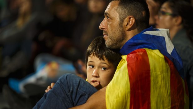 A man and his child listen to a televised speech by Mariano Rajoy, Spain's Prime Minister.