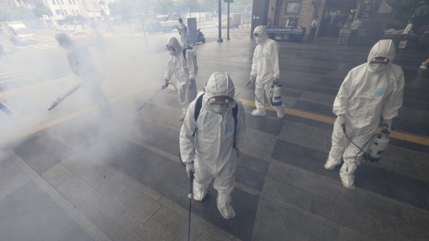 Workers spray antiseptic solution as a precaution against the spread of MERS in Seoul last year. 