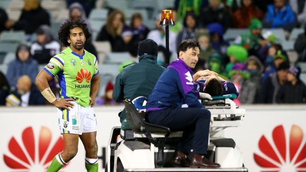 Storm star Billy Slater is taken from the field after a tackle by Raiders forward Sia Soliola, left.