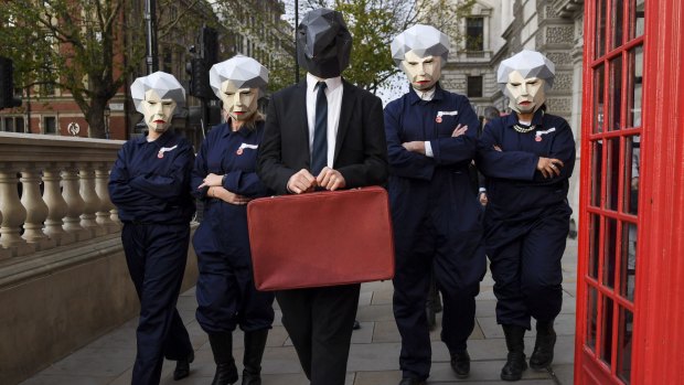 Demonstrators wearing masks depicting  Primer Minister Theresa May protest ahead of the annual budget statement in the House of Commons in London on Wednesday.