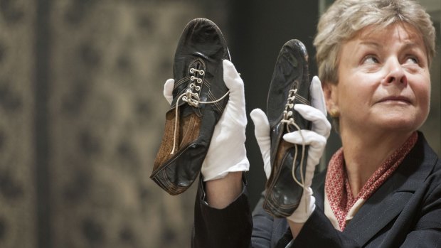 A Christie's employee holds running shoes worn by Sir Roger Bannister, which sold in London at auction.