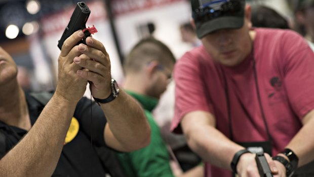 Attendees look over pistols on display at the NRA convention in April in Nashville. 