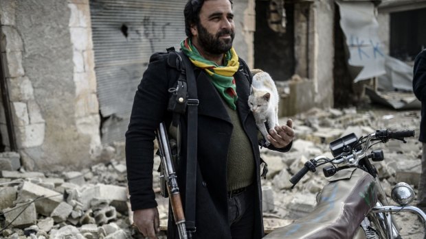 A Kurdish fighter holds a cat in the centre of Kobane.