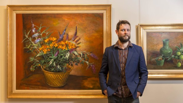 Artist Ben Quilty standing in front of Margaret Olley's artwork being exhibited for the first time at the Philip Bacon Galleries.