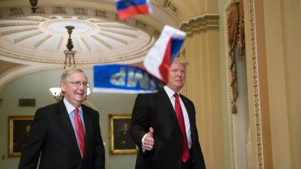 Small Russian flags bearing the word "Trump" are thrown by a protester towards President Donald Trump, as he walks with Senate Majority Leader Mitch McConnell, on Wednesday.