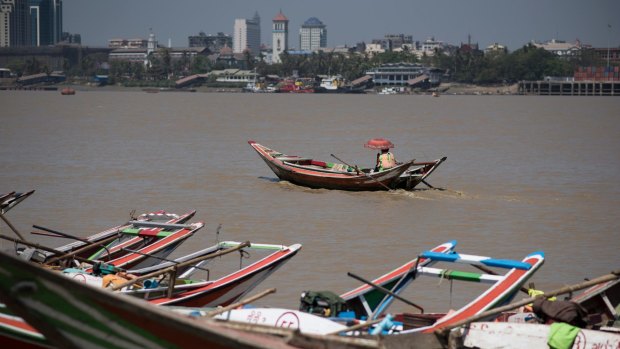 Long tail boats in the Yangon river at Dala, Myanmar with the country's largest city, Yangon, across the water.