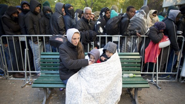 Refugees try to keep warm as they wait for registration in Berlin.