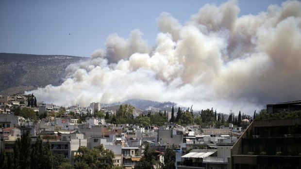 Smoke from a forest fire covers the hillsides near eastern Athens.