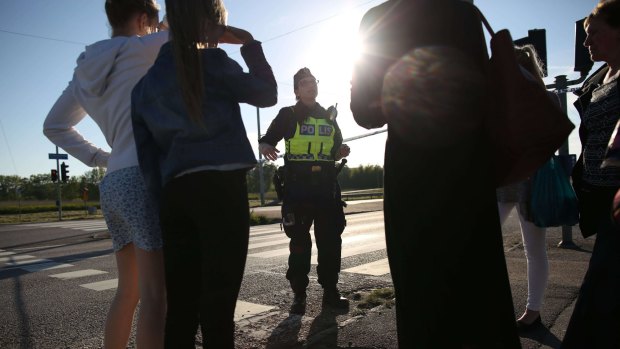 A police officer speaks to eyewitnesses after a car exploded in a roundabout in Gothenburg, Sweden.