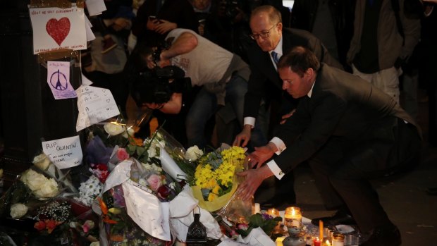 Australia's Energy Minister Josh Frydenberg, right, and Ambassador Stephen Brady place flowers at the Bataclan memorial in Paris on Monday.